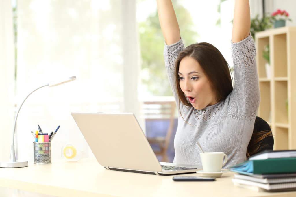 Happy excited woman who booked a Money Power Workshop on her laptop